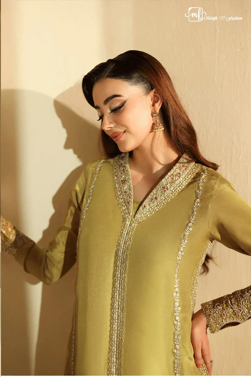 Woman wearing a green traditional outfit with gold embroidery against a beige background
